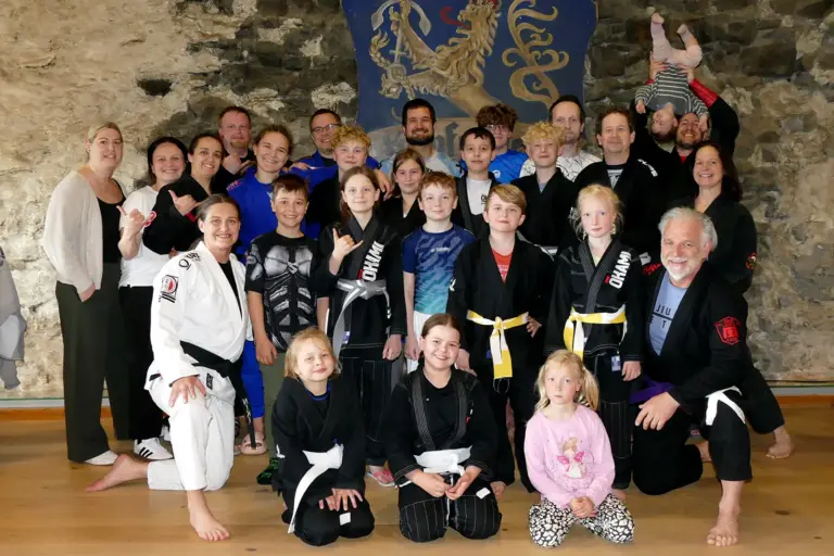 Eine Gruppe von Personen in Sportkleidung posiert vor einem Wappen