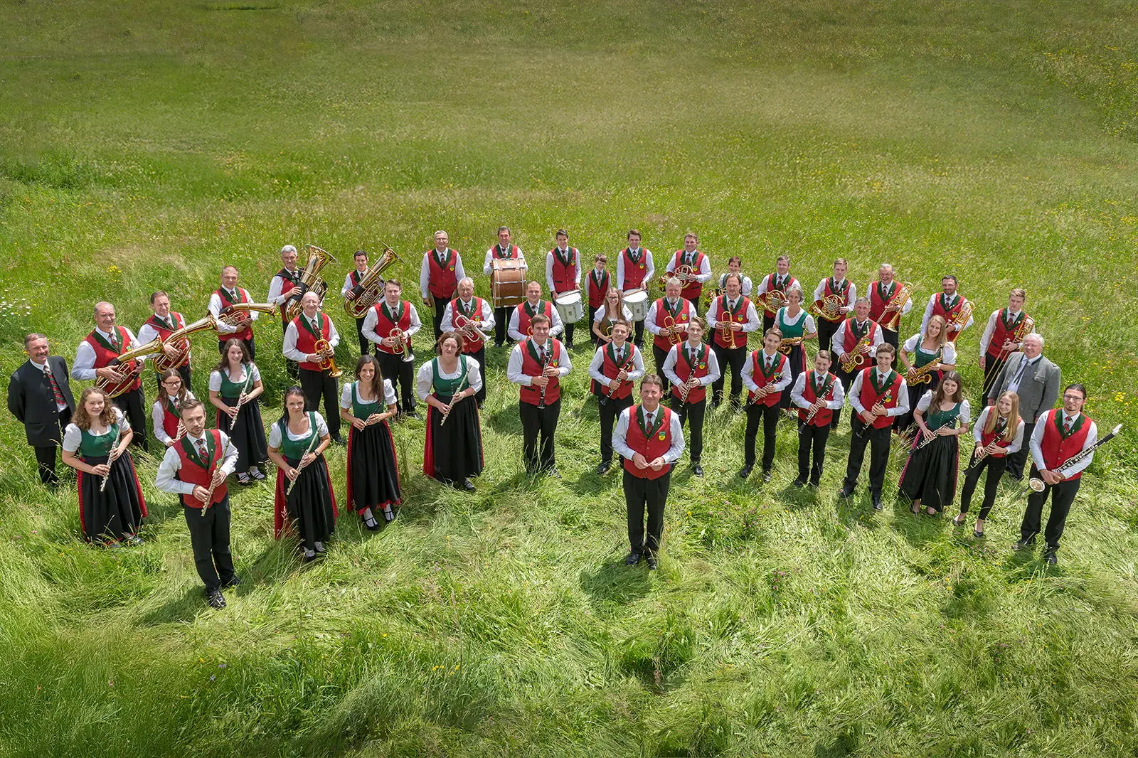 Eine Musikkapelle in Tracht steht auf einer Wiese
