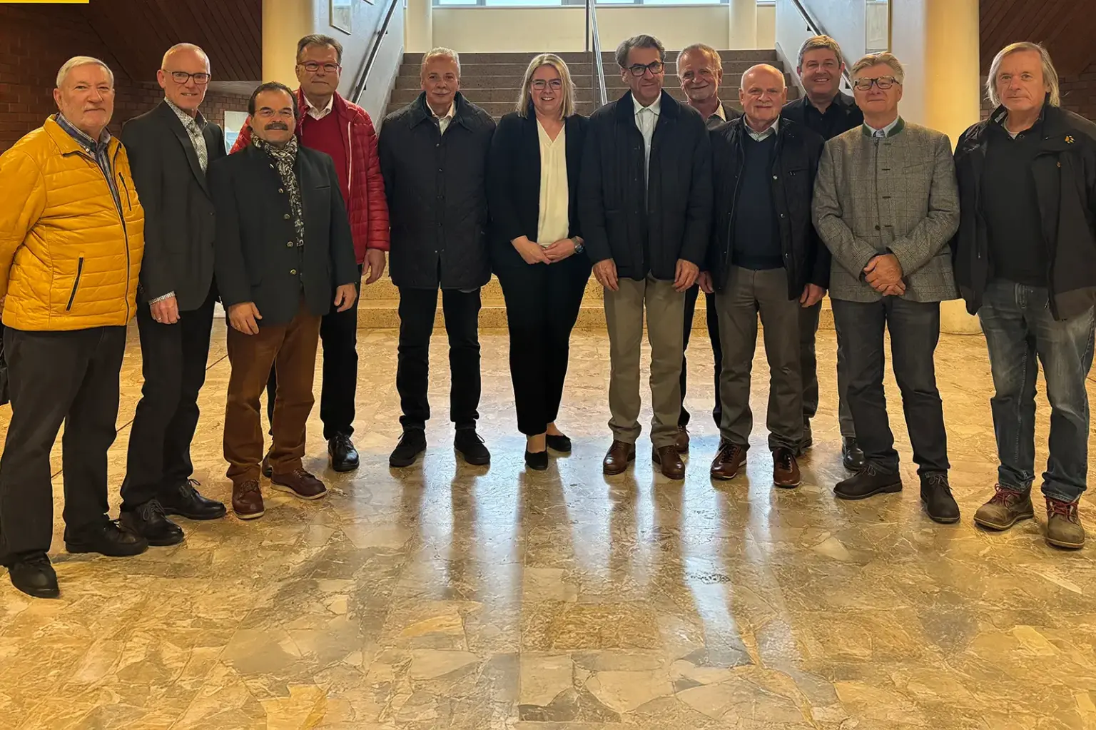 Eine Gruppe von älteren Personen steht in einer Aula