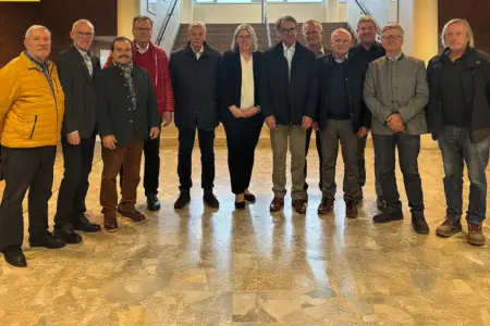 Eine Gruppe von älteren Personen steht in einer Aula