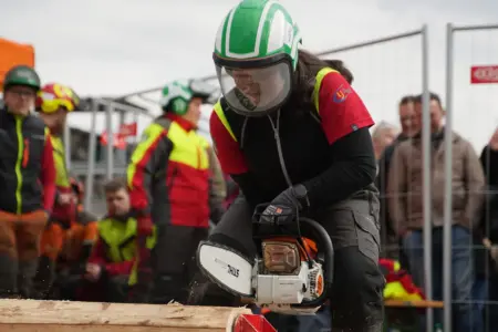 Eine junge Frau schneidet Holz mit einer Kettensäge