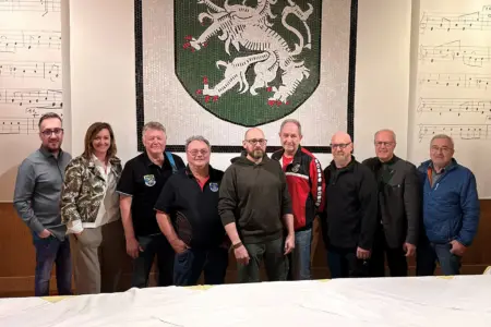 Neun Personen stehen vor einer Wand mit dem steirischen Wappen