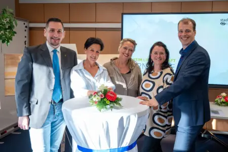 Zwei Männer und drei Frauen stehen an einem kleinen Tisch