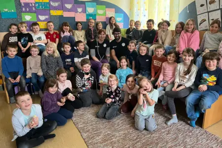 Eine große Gruppe von Kindern und zwei Erwachsene mit einigen Küken in einem grroßen Raum