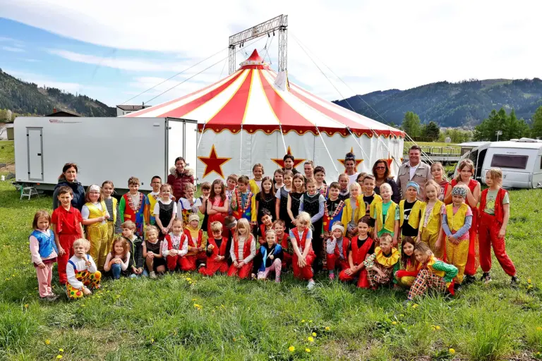 EIne große Gruppe von Kindern vor einem Zirkuszelt