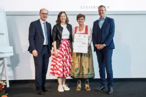 Zwei Männer und zwei Frauen halten eine Urkunde