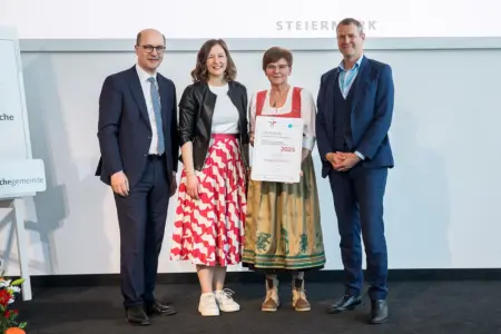 Zwei Männer und zwei Frauen halten eine Urkunde