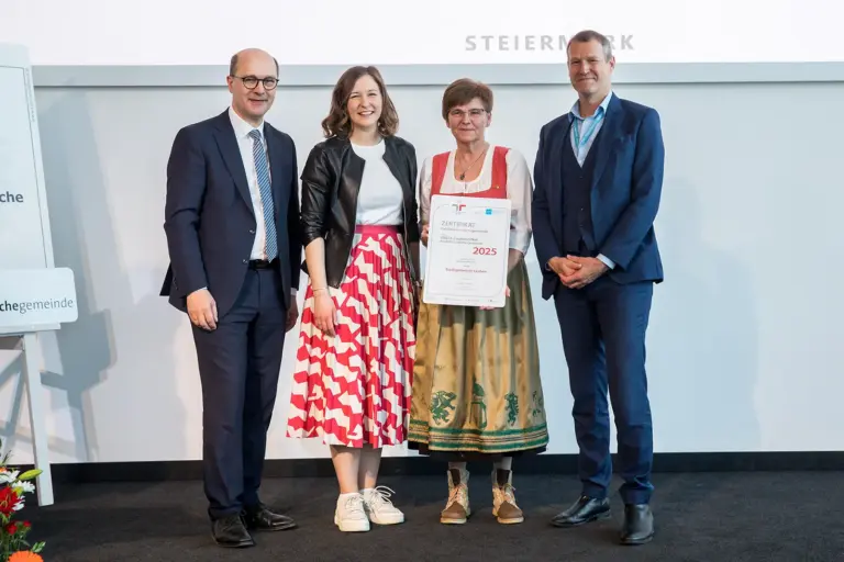 Zwei Männer und zwei Frauen halten eine Urkunde