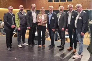 Sieben Männer und eine Frau stehen in einem großen Veranstaltungssaal