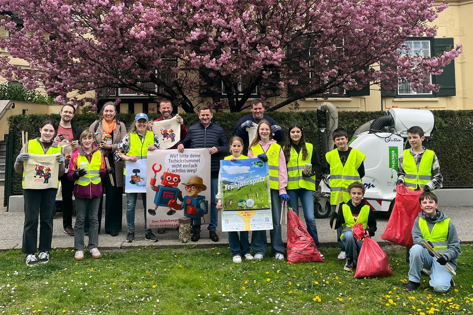 Eine Gruppe von Jugendlichen und Erwachsenen mit Plakaten und Müllsäcken