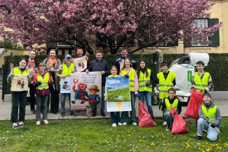 Eine Gruppe von Jugendlichen und Erwachsenen mit Plakaten und Müllsäcken