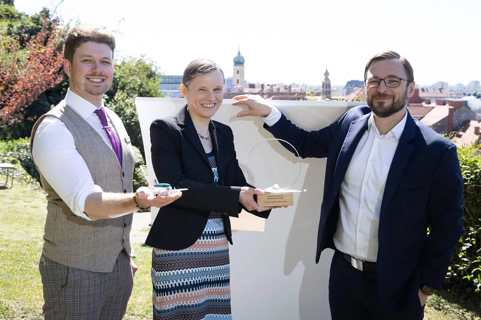 Zwei Männer und eine Frau halten Preise in der Hand
