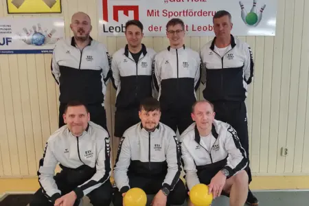 Sieben Männer des ESV Leoben posieren in einheitlichen Trainingsanzügen in einer Kegelhalle; drei knien vorne mit gelben Kugeln, vier stehen dahinter vor einer Wand mit Vereins- und Sponsorenplakaten.