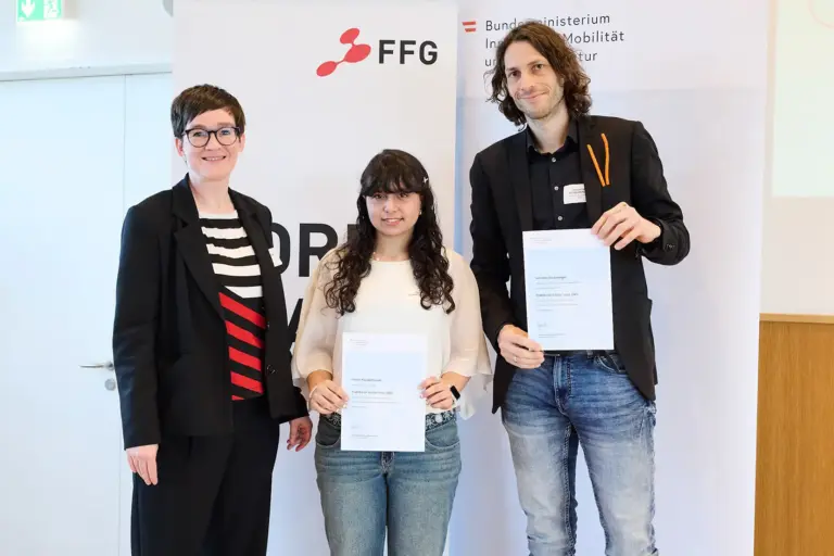 Eine Frau, ein Mädchen und ein Mann halten Urkunden