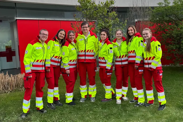 Acht Personen in Uniform stehen auf einer Wiese