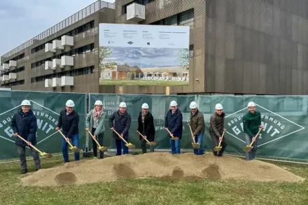 Eine Gruppe von Personen mit Helmen und Schaufeln vor einer Schautafel
