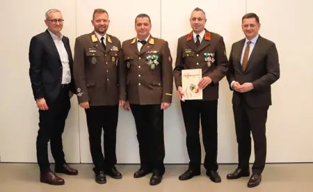 Fünf Männer, zum Teil in Uniform, präsentieren eine Urkunde