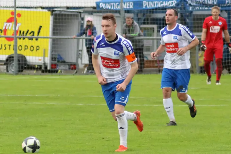 Ein Fußballkapitän läuft dem Ball nach.