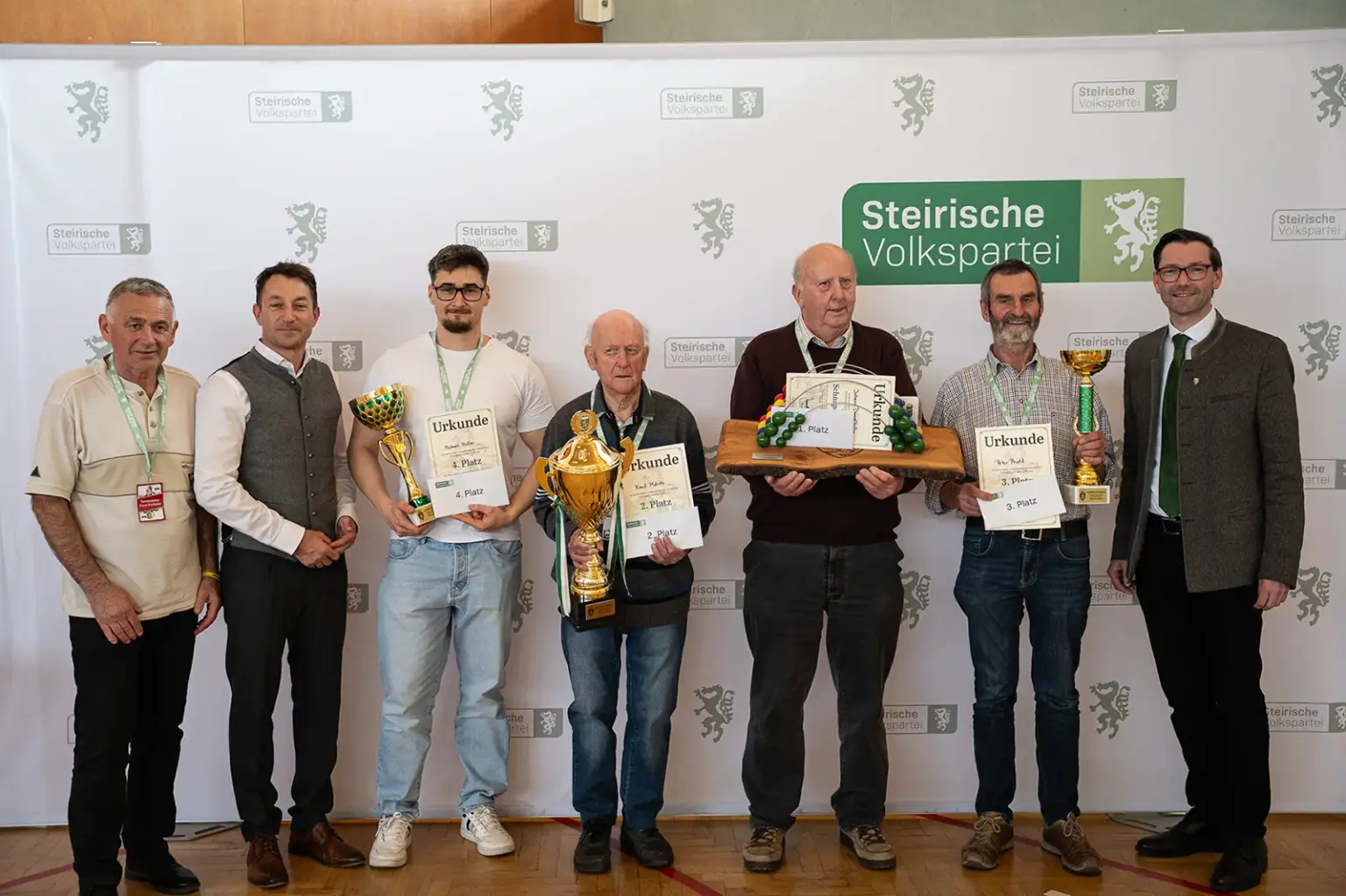 Sieben Männer präsentieren Pokale und Urkunden