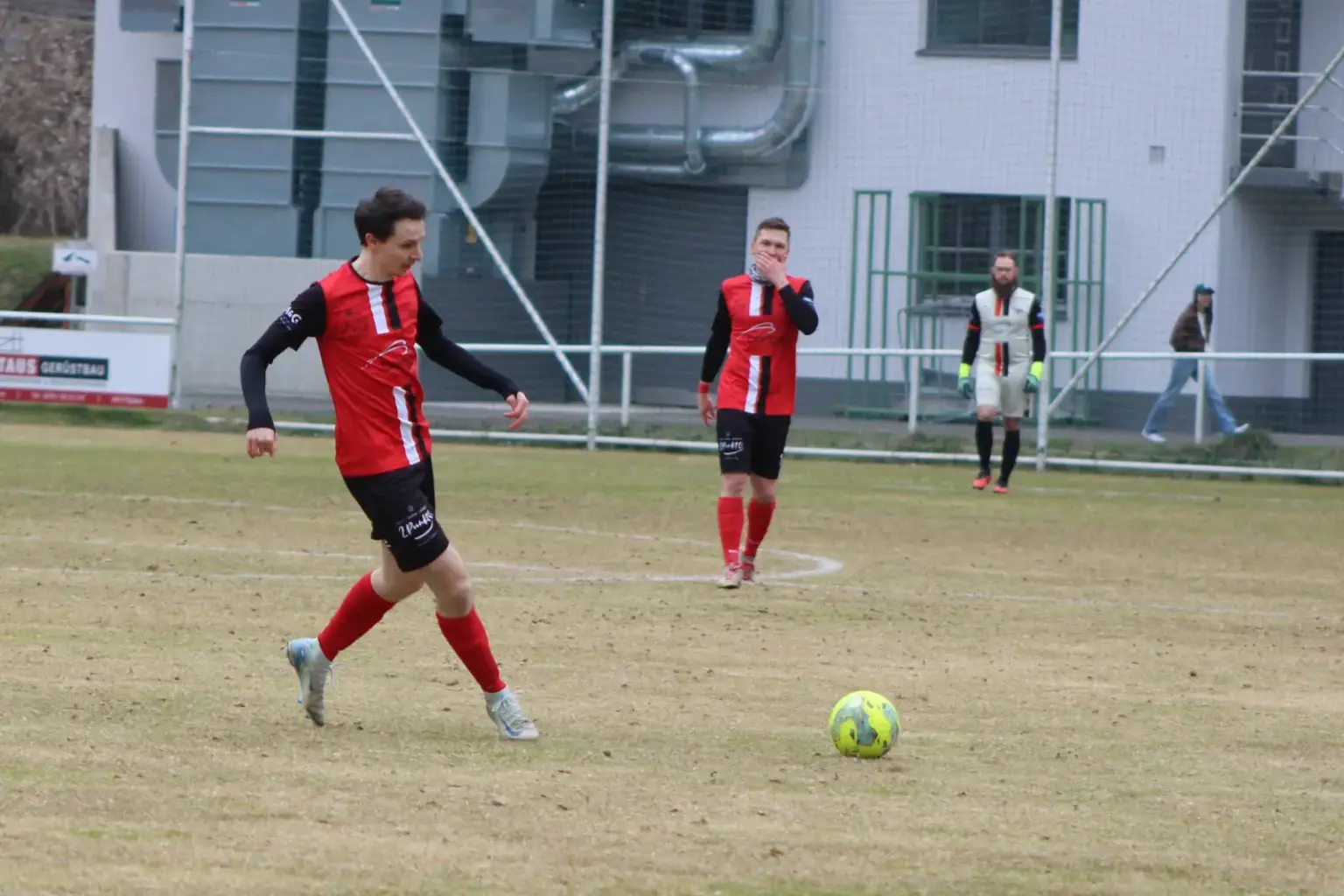 Drei Fußballer und ein gelber Ball.