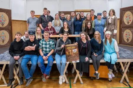Eine Gruppe von jungen Menschen sitzt und steht auf einer Bühne.