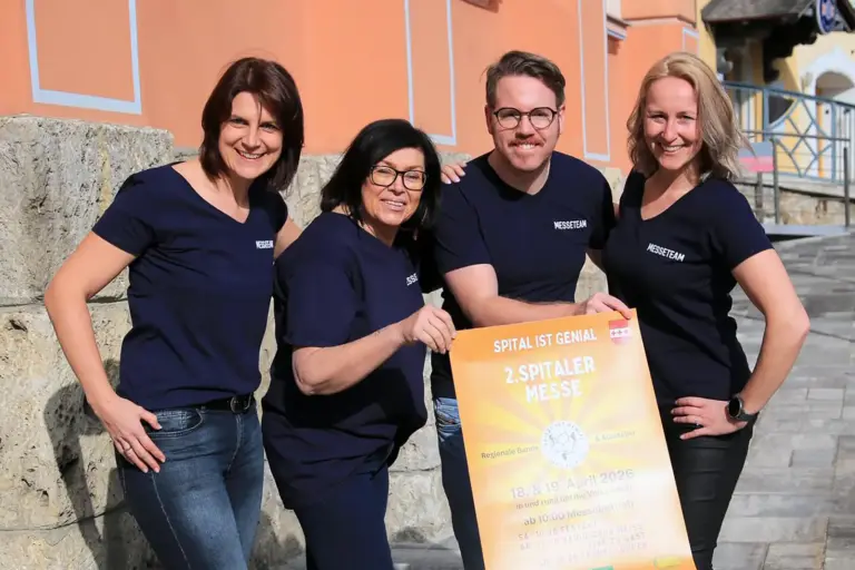 Drei Frauen und ein Mann halten gemeinsam ein Plakat.