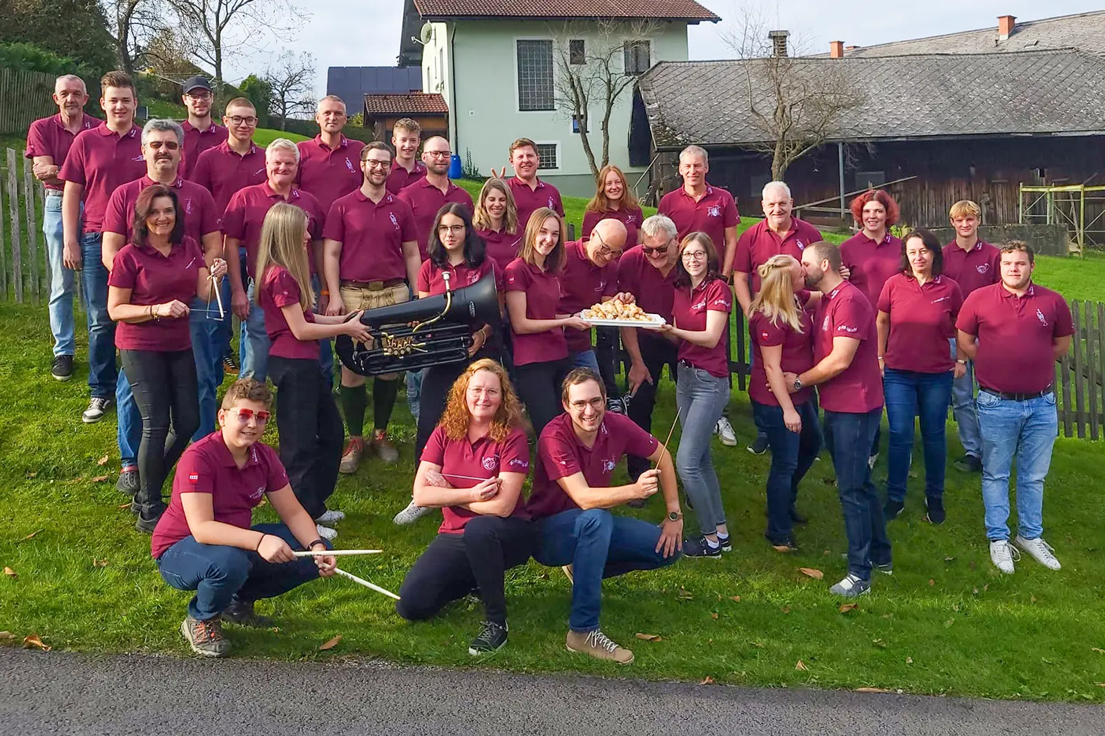 Eine große Gruppe von Personen in weinroten T-Shirts steht auf einer Wiese