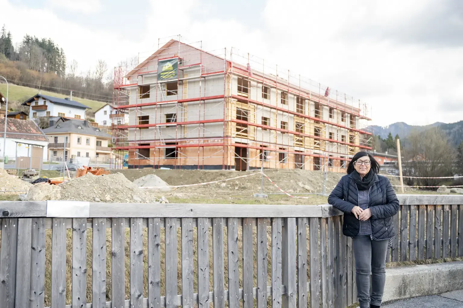 Eine Frau steht vor einem großen Wohnhaus.