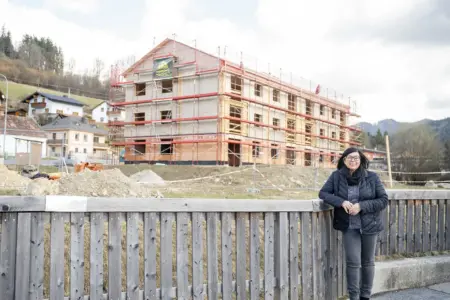 Eine Frau steht vor einem großen Wohnhaus.
