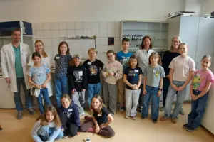 Eine Gruppe von Kindern und Erwachsenen in einem Raum mit vielen Schränken