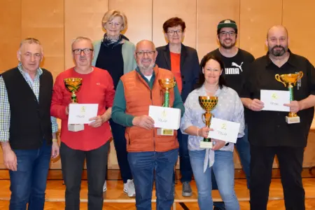 Acht Personen posieren mit vier Pokalen