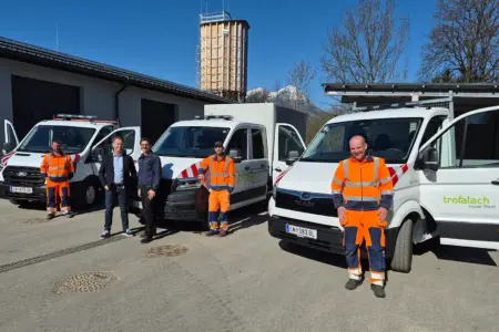 Fünf Personen stehen vor drei Fahrzeugen