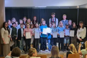 Eine Gruppe von Kindern und Jugendlichen steht mit Urkunden auf einer Bühne