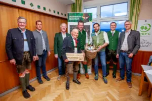 Acht Männer in Trachtenkleidung bei einer Preisverleihung