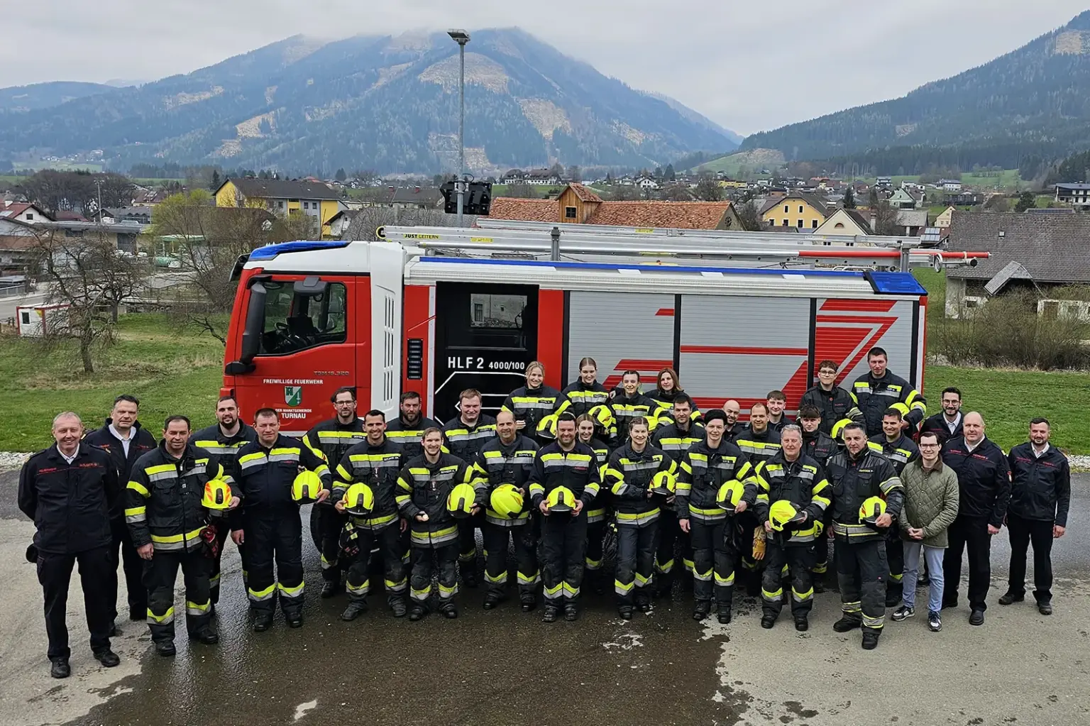 Eine große Gruppe von Personen in Uniform steht vor einem Feuerwehrauto