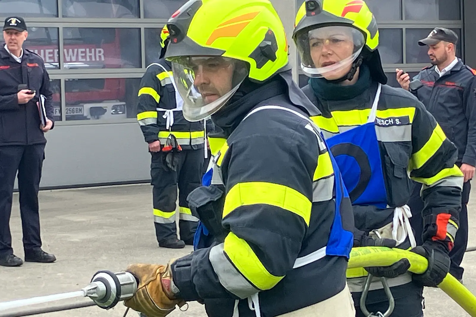 Zwei Feuerwehrleute halten einen Schlauch