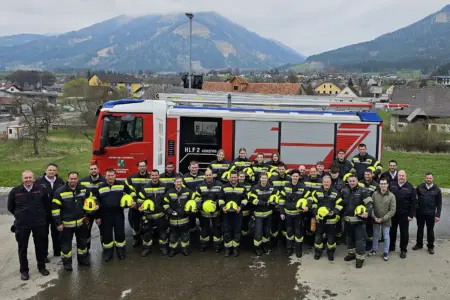 Eine große Gruppe von Personen in Uniform steht vor einem Feuerwehrauto