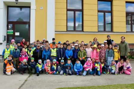 Eine große Gruppe von Kindern stehen mit einigen Erwachsenen vor einem Haus