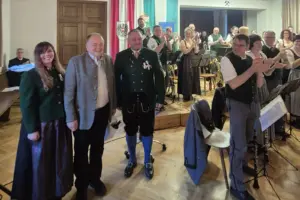 Eine Musikkapelle in Tracht applaudiert einem älteren Mann