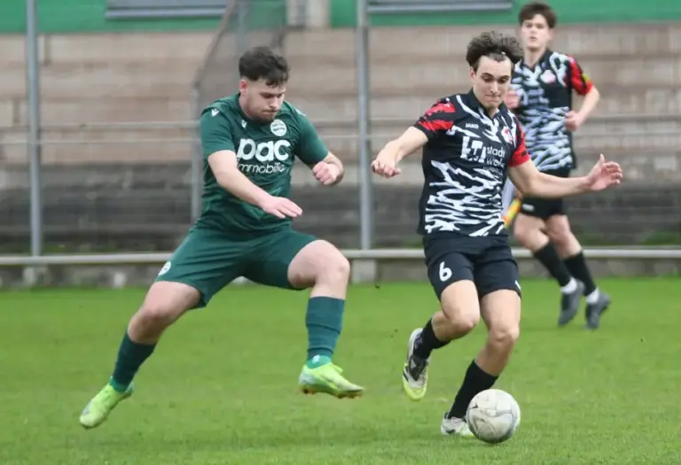 Zwei Spieler laufen dem Ball hinterher.