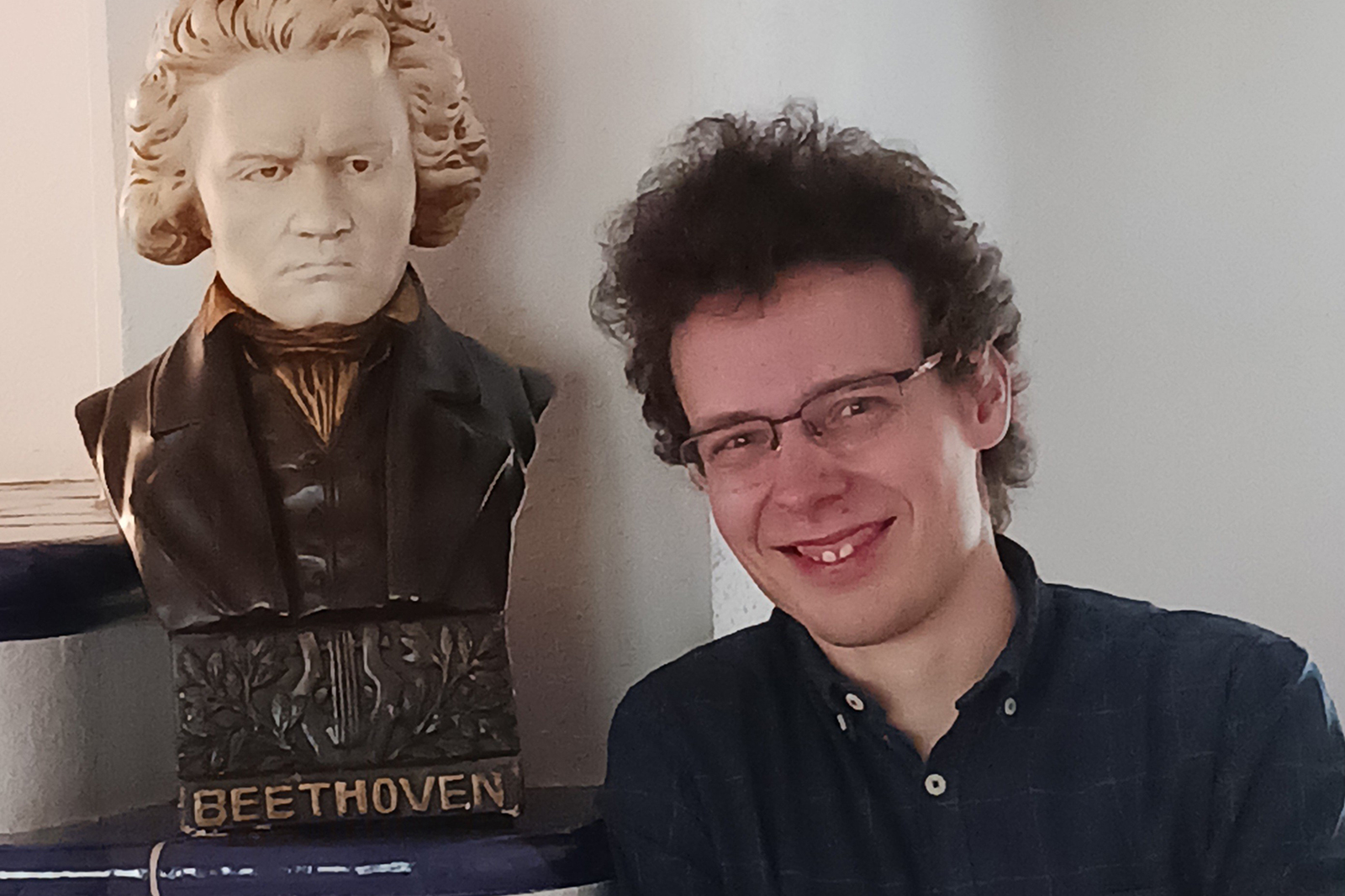 Ein junger Mann mit Brille neben einer Beethoven-Büste