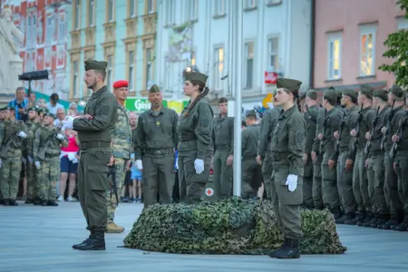 Frauen und Männer in Militäruniform stehen an einem Fahnenmasten
