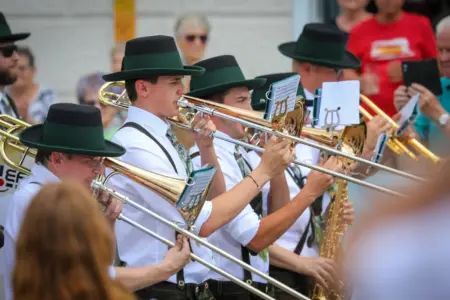 Posaune, Saxophon und Flügelhorn spielende Mitglieder eines Blasmusikorchesters in Trachtenkleidung