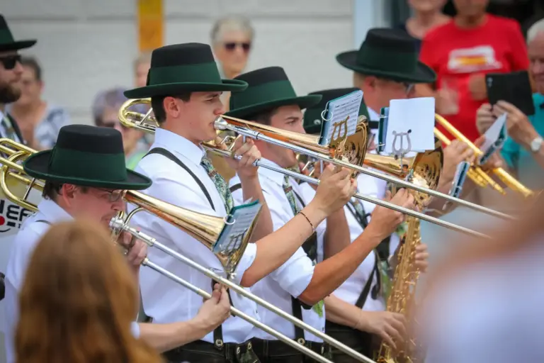 Posaune, Saxophon und Flügelhorn spielende Mitglieder eines Blasmusikorchesters in Trachtenkleidung