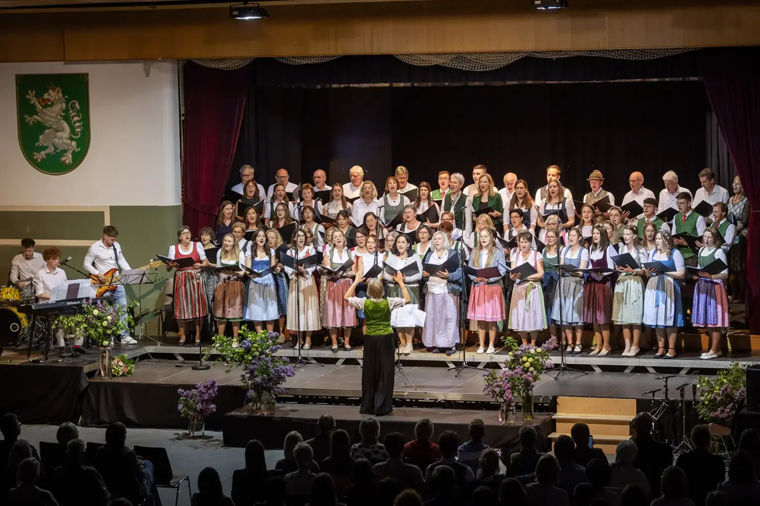 Stimmgewaltiger Abend in Birkfeld Ein großer gemischter Chor in Trachtenkleidung singt auf einer Bühne