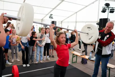 Erste Brucker Vereinsmesse Ein kleines Mädchen versucht sich in einem Messezelt als Gewichtheberin