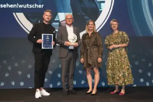 Zwei Männer und zwei Frauen stehen mit einer Trophäe auf einer Bühne