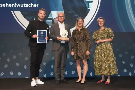 Zwei Männer und zwei Frauen stehen mit einer Trophäe auf einer Bühne