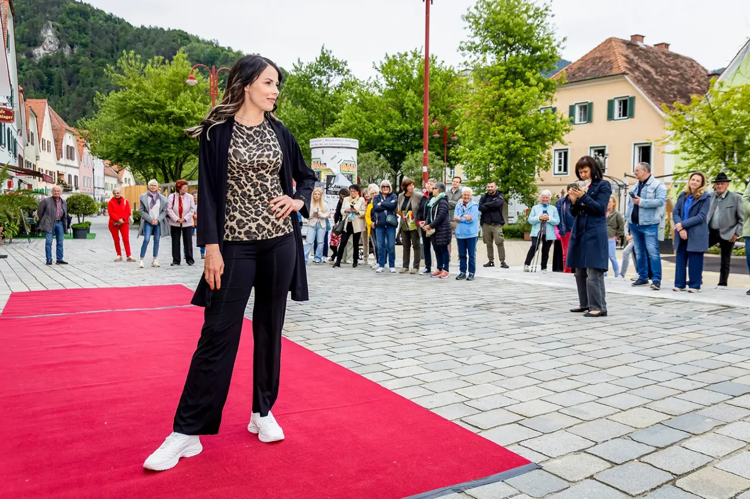 Markt, Mode & Sport in Frohnleiten: Im Mai geht’s noch richtig rund Eine Frau steht auf einem roten Teppich auf einem innerstädtischen Platz, im Hintergrund Publikum
