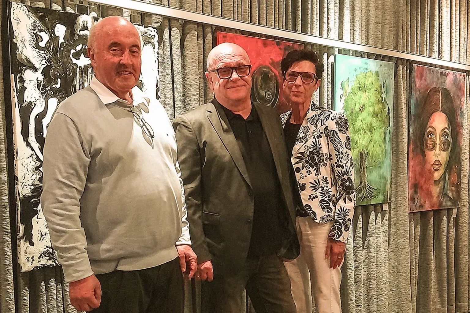 Ausstellung beim Filmklub Kapfenberg Zwei Männer und eine Frau stehen vor einer Wand mit Bildern